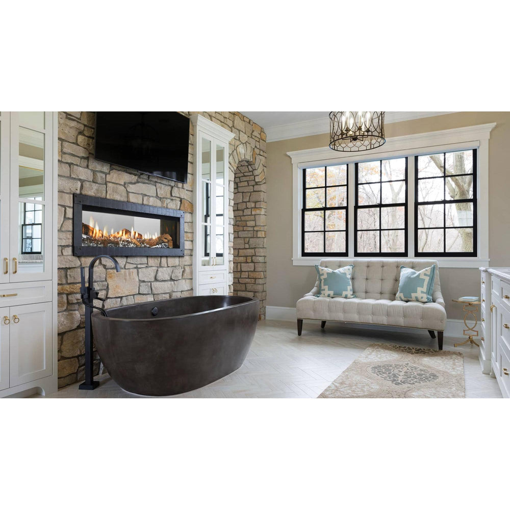 Upscale bathroom with see-through linear gas fireplace on stone wall over modern freestanding tub. — official Mezzo Double-Sided Linear Gas Fireplace series image; may show a different size and separately selected options
