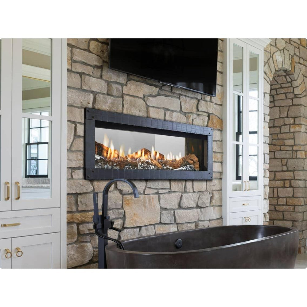 Heat & Glo Mezzo See-Through AU 48" linear gas fireplace on stone wall over bathtub with TV above. — official Mezzo Double-Sided Linear Gas Fireplace series image; may show a different size and separately selected options