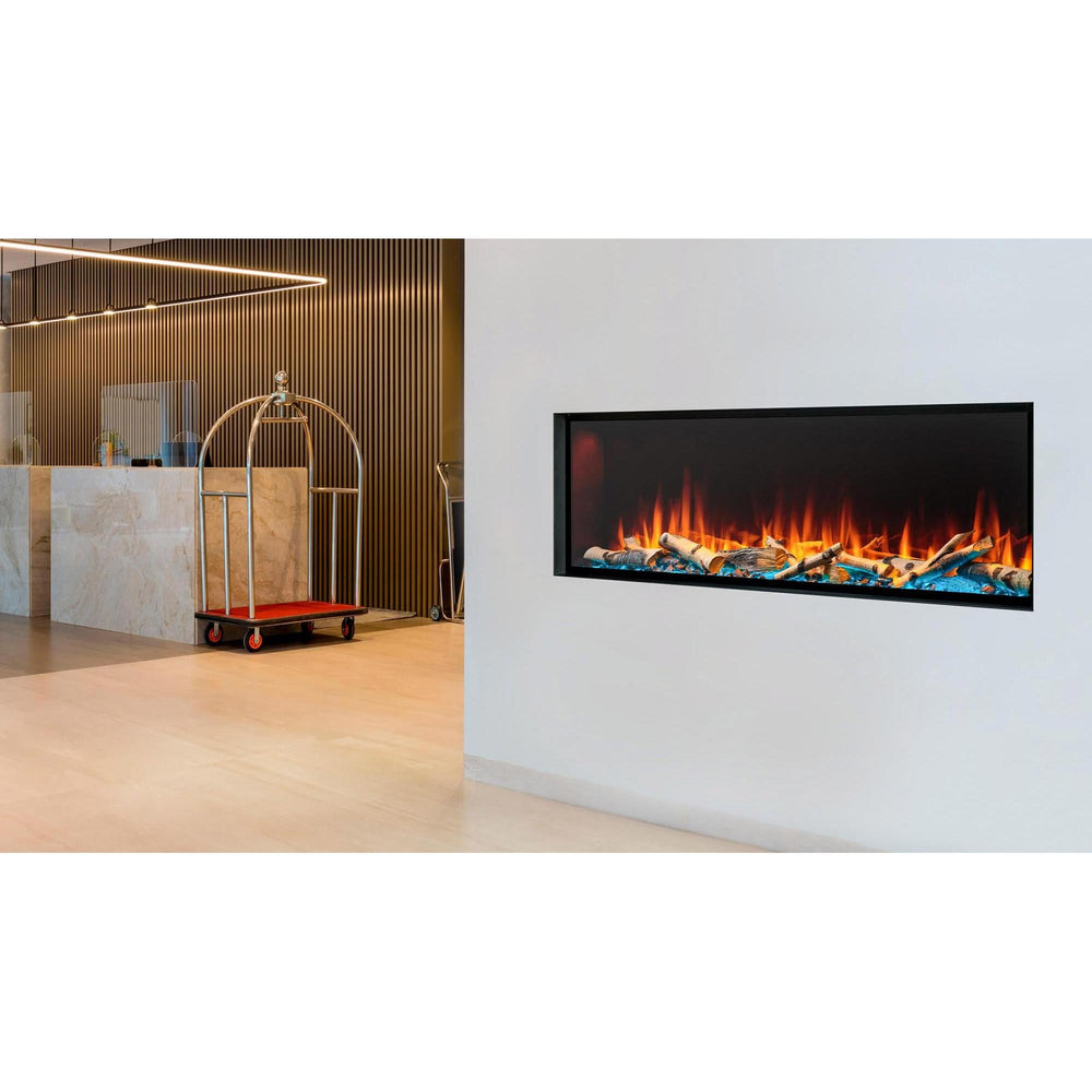 SimpliFire Forum 55: In an upscale hotel lobby is a corner wall with linear electric fireplace with orange flames, birch logs and minimal frame. Optional logs and surrounding finishes may be shown.